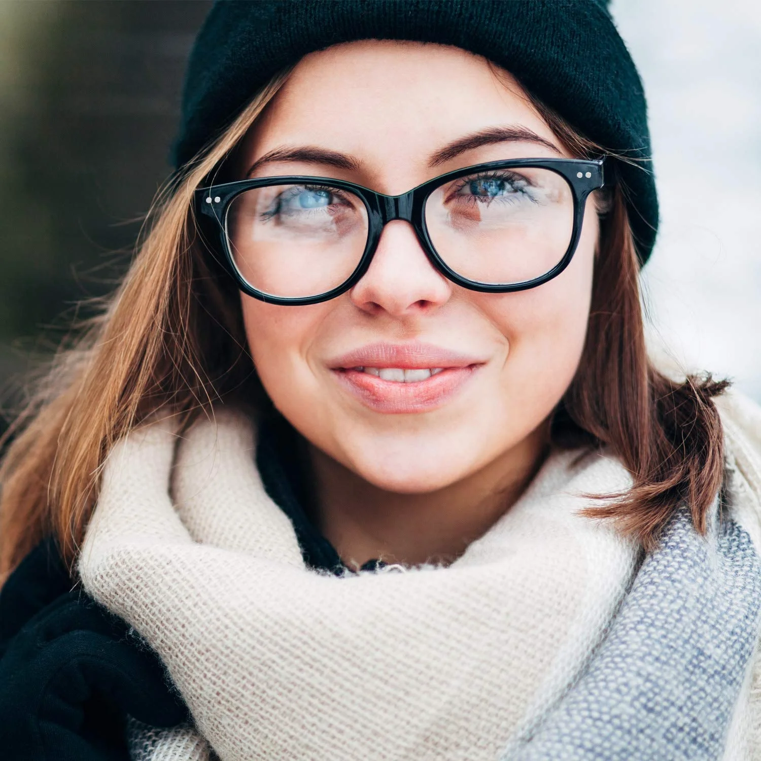 The oversized clear-lens frame in black, under a beanie and a scarf